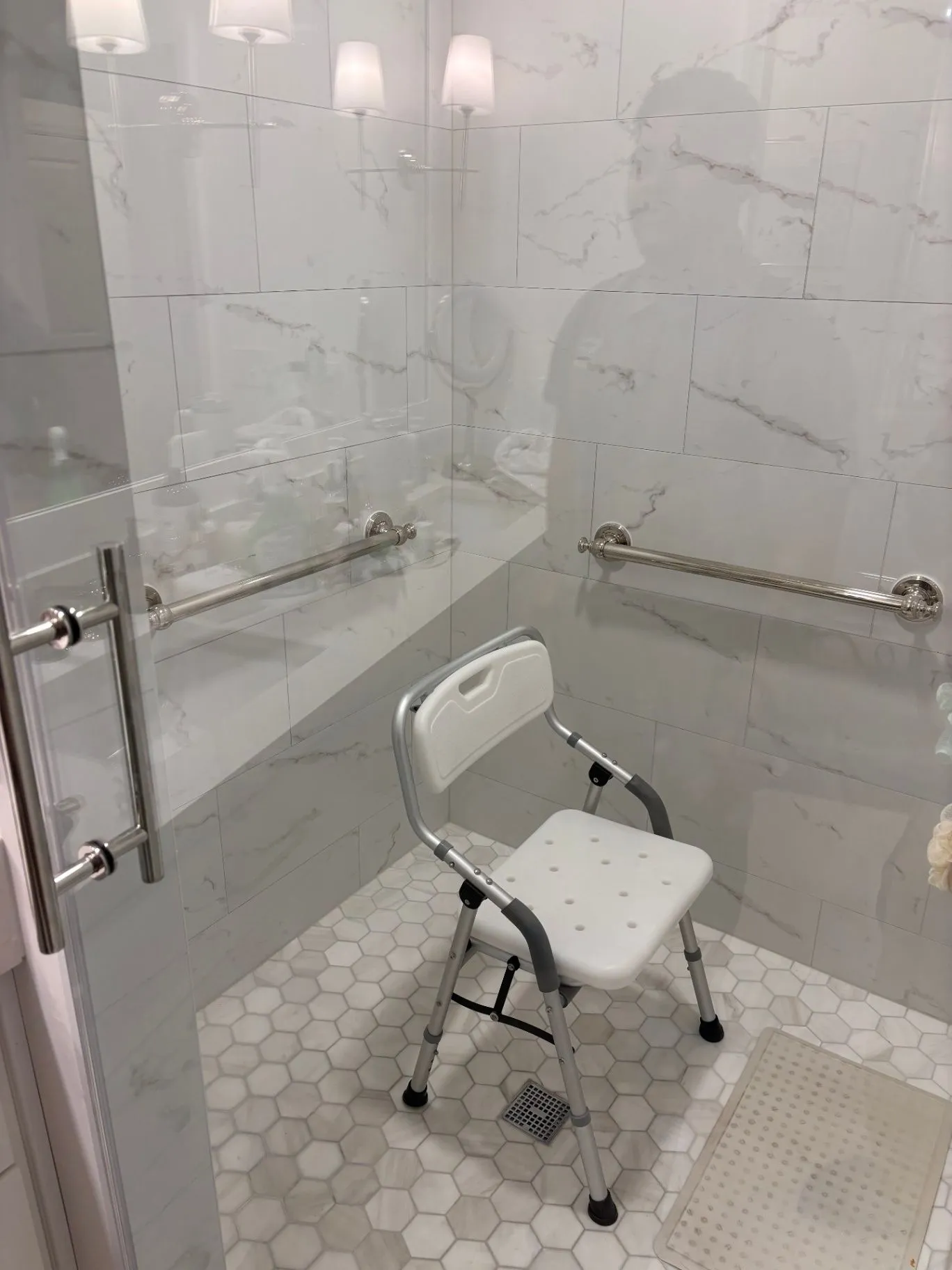 Tiled shower interior with a shower chair and horizontal grab bars on two walls